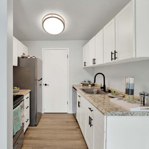 Thumbnail 4 of 13 A kitchen with white cabinets and a granite countertop.