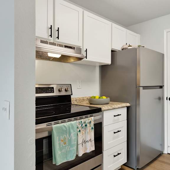 Thumbnail 5 of 13 A kitchen with a stove top oven and a refrigerator.