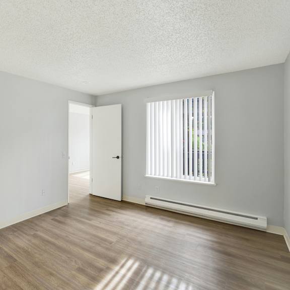 Thumbnail 8 of 13 A room with a wooden floor and a window with blinds.