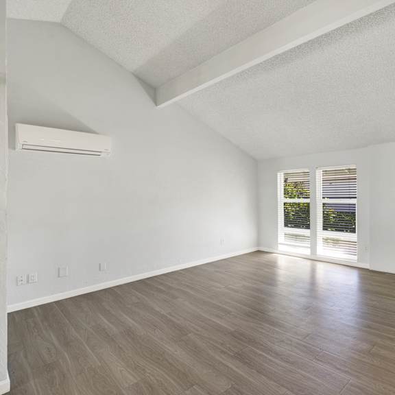 Thumbnail 10 of 18 A spacious room with wooden flooring and a large window.