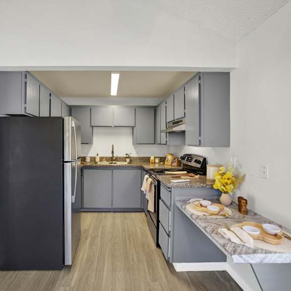 Thumbnail 8 of 18 A kitchen with a black refrigerator and wooden floors.