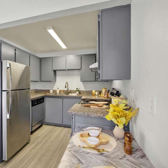 Thumbnail 18 of 18 A modern kitchen with a stainless steel refrigerator and a table set for two.