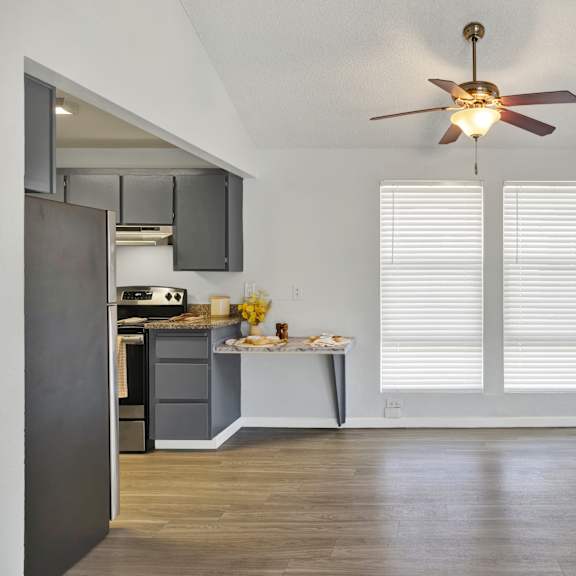Thumbnail 3 of 18 A kitchen with a ceiling fan and a dining table with chairs.