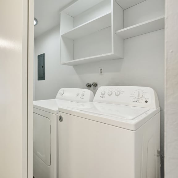 Thumbnail 12 of 18 A white washing machine and dryer in a small laundry room.