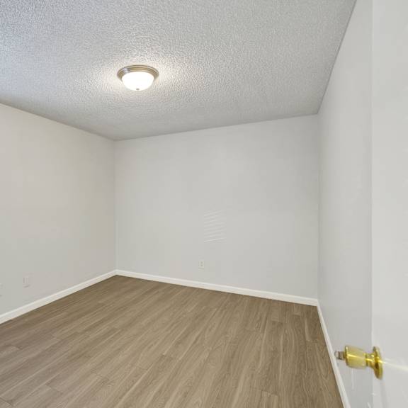 Thumbnail 14 of 18 A room with a wooden floor and a window with blinds.