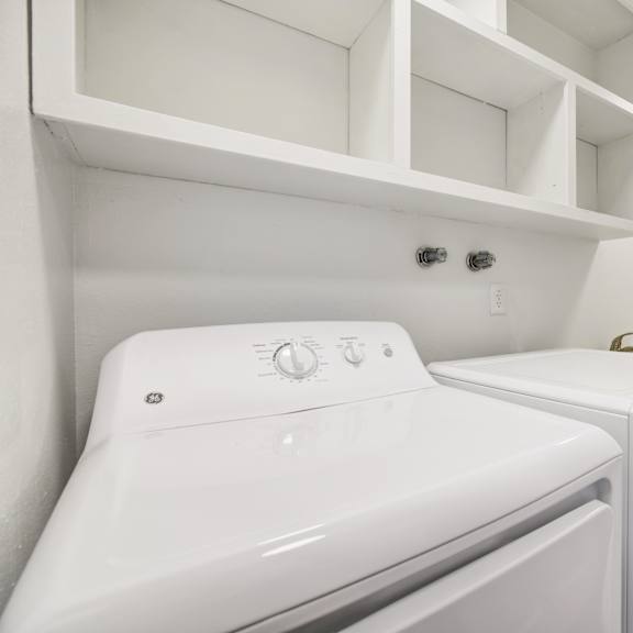 Thumbnail 11 of 18 A white washing machine and dryer in a laundry room.