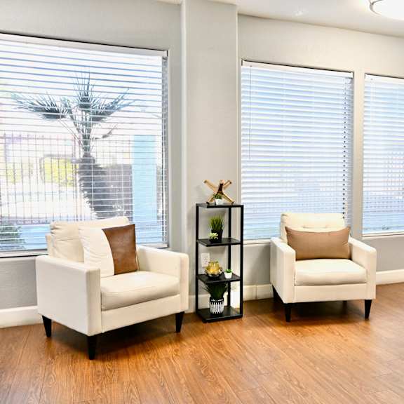 two white chairs are placed in a room with a clock on the wall.
