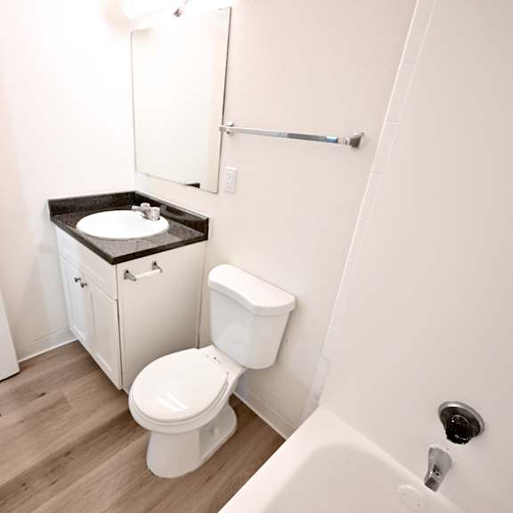 a white toilet with a black counter top in a small bathroom.