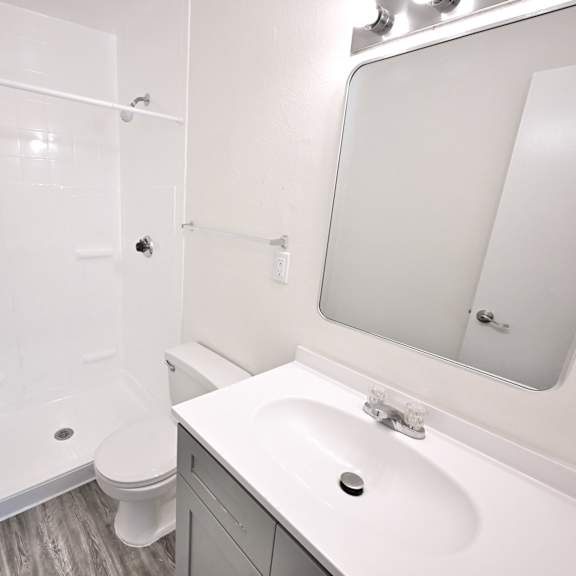 a white bathroom with a toilet, sink, and shower.