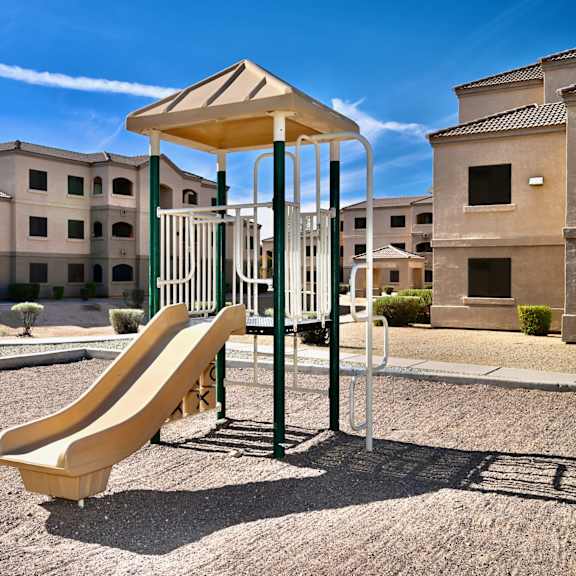 a playground with a yellow slide in front of a building.