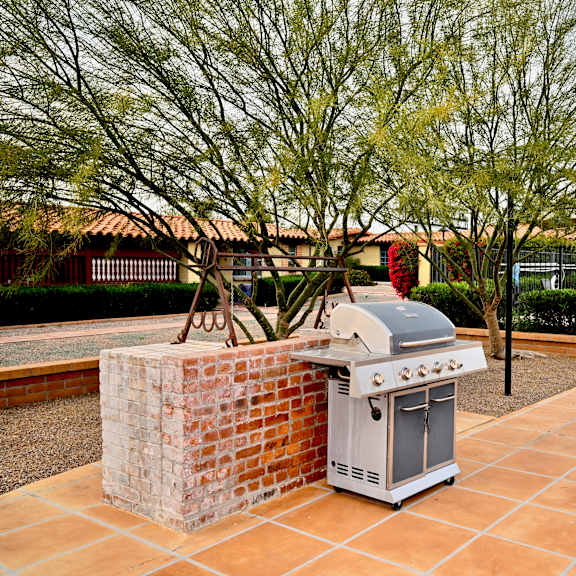 a brick chimney sits behind a built-in grill.