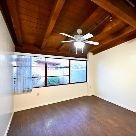 a room with a ceiling fan and two windows.
