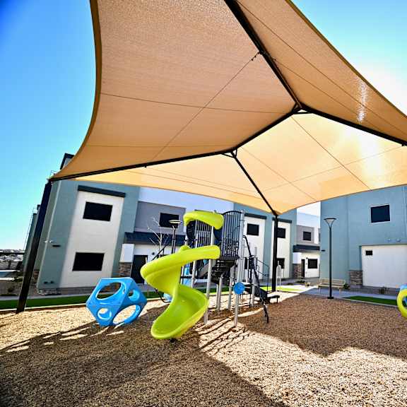a playground with a yellow canopy and a blue and yellow slide.