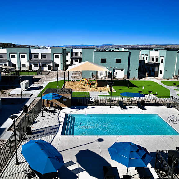a pool surrounded by blue umbrellas and chairs.