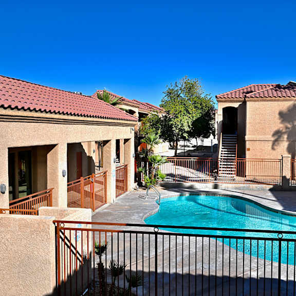 a pool in front of a house with a black fence.