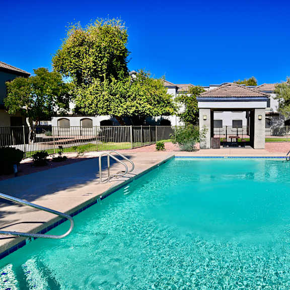 a swimming pool in front of a building with a fence around it.