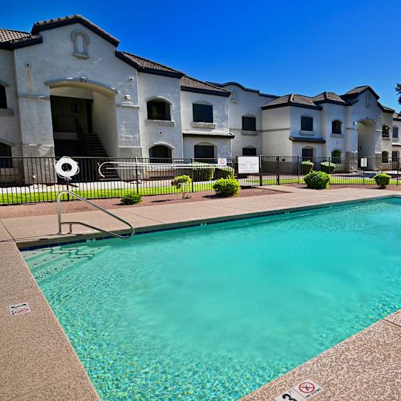 a swimming pool in front of a building with a clear blue sky.