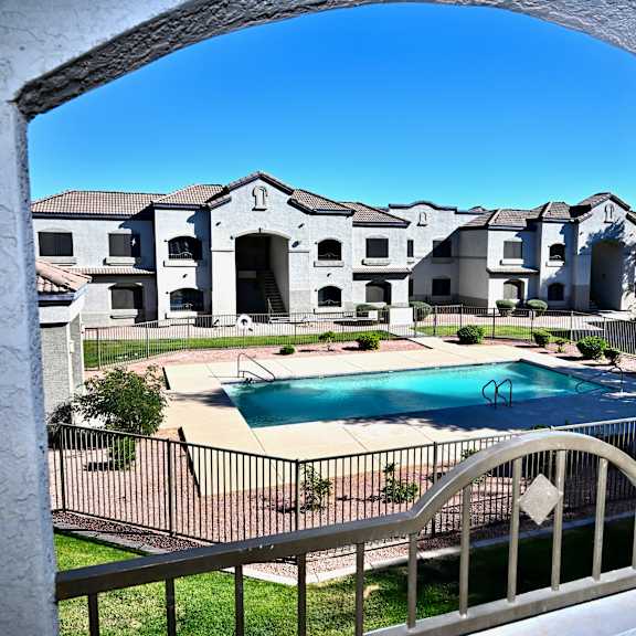 a view of a pool through an arched window with a fence in the foreground.