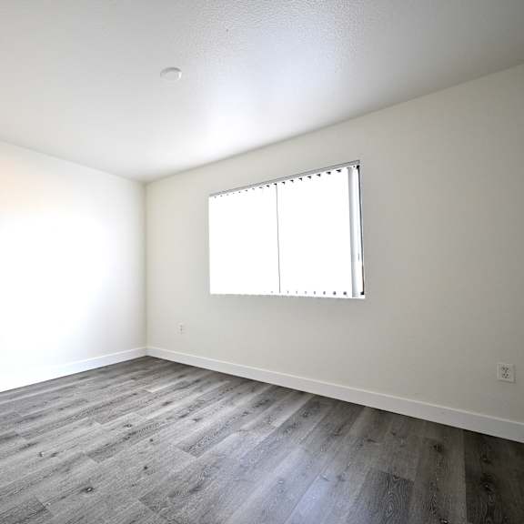 a room with a window and wooden flooring.