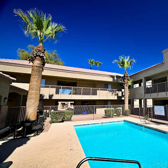 a pool surrounded by apartment buildings and palm trees.