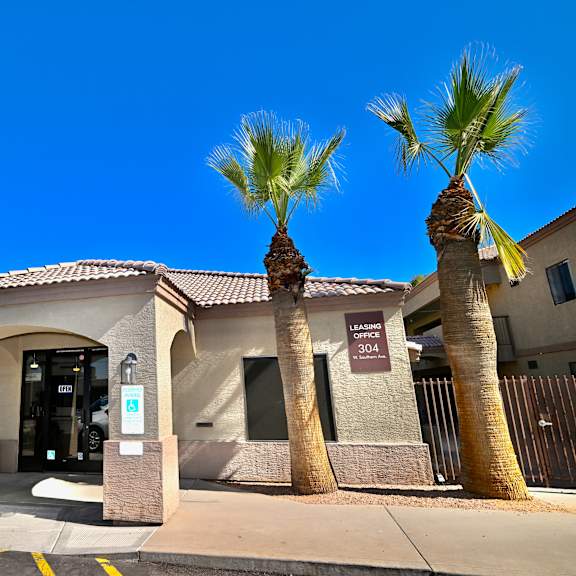 a building with palm trees in front and a car parked in front of it.