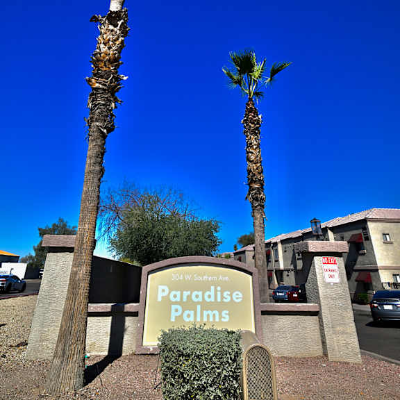 two palm trees in front of a sign that says paradise palms.