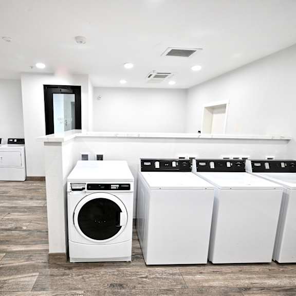 a row of white washing machines are lined up in a laundry room.