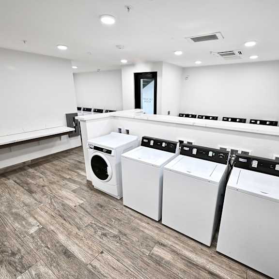 a row of white washing machines in a laundry room.