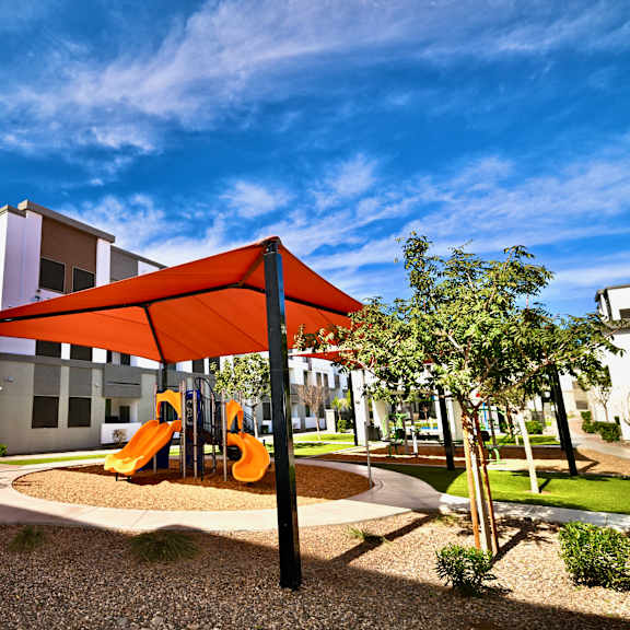 a playground with a red canopy is located in front of a white building.