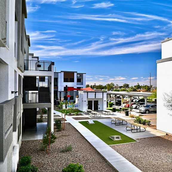 a courtyard with a white building and a tree.
