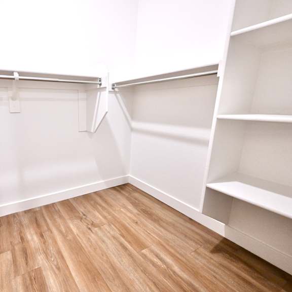 empty white shelves in a room with wooden flooring.