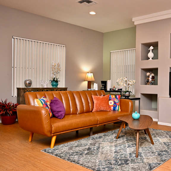 a living room with a brown leather couch and a blue rug.