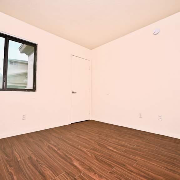 a room with a window and wooden flooring.