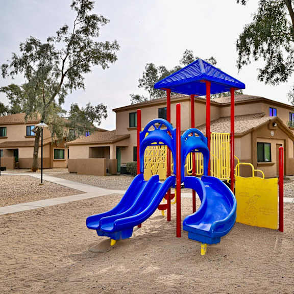 a playground with a blue slide and a red and yellow structure.