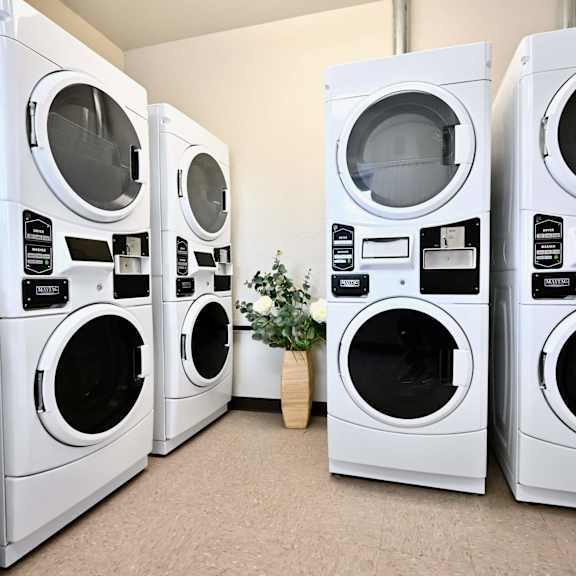 a row of white front load washing machines in a laundromat.