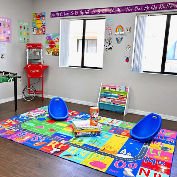 a brightly colored children's playroom with a foosball table, a soft play area, and a corkboard with various papers pinned to it.