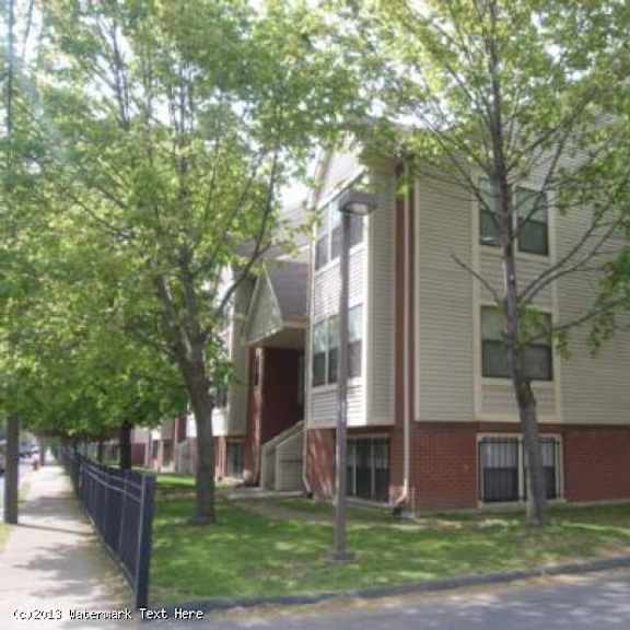 a tree-lined street with apartment buildings on either side.
