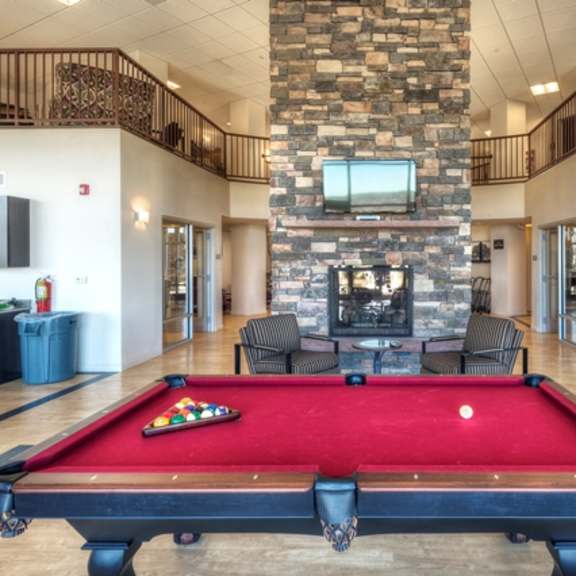 a pool table is in the middle of a room with a stone wall and a tv.