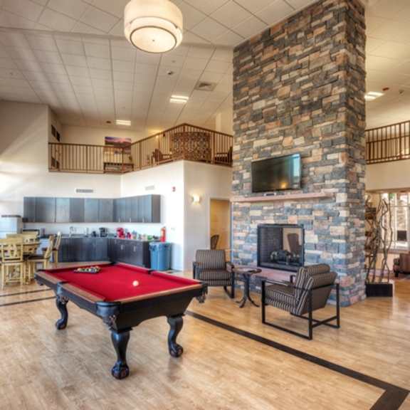 a room with a pool table and a stone fireplace.
