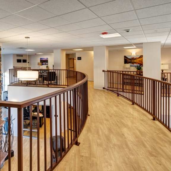 a view of a hallway with a stone wall and a railing.