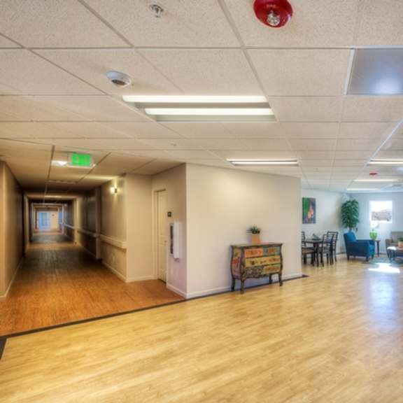 a hallway with a bench and chairs on the right side.