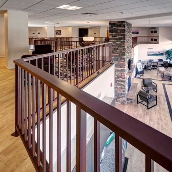 a balcony with a railing overlooks a room with a pool table and a couch.