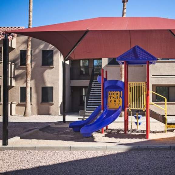 a playground with a red canopy and a blue slide.