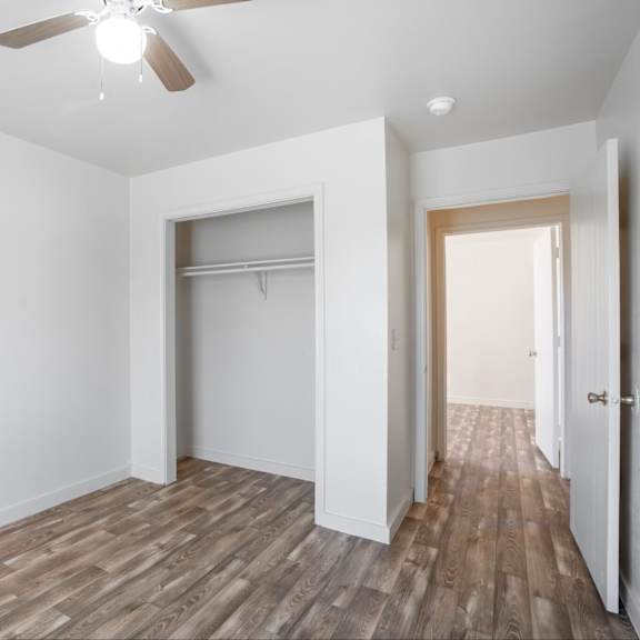 a room with a ceiling fan and wooden flooring.