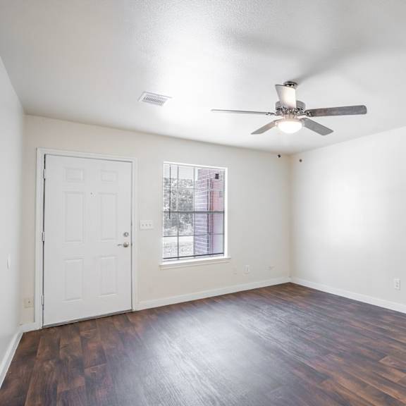 a room with a ceiling fan and a window with a view of a city.