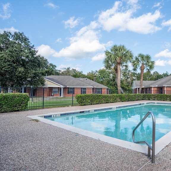 a swimming pool surrounded by palm trees and a building in the background.