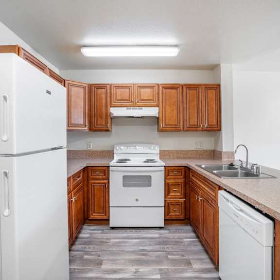 a white refrigerator stands in a kitchen with wooden cabinets and a white stove.