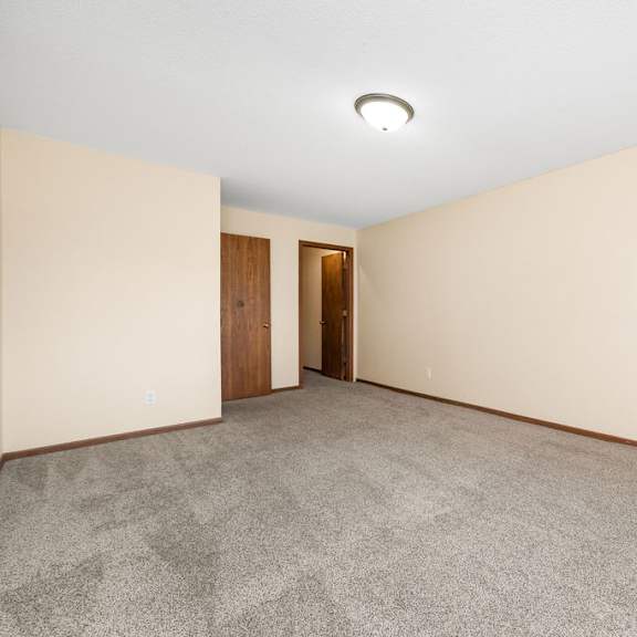 a room with a carpeted floor and two doors.