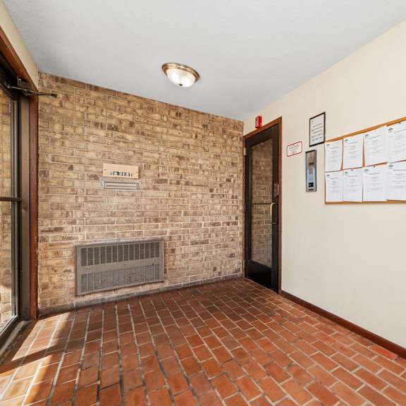 a hallway with a brick wall and a bulletin board on the wall.