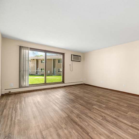 a room with wooden flooring and a sliding glass door leading to a balcony.